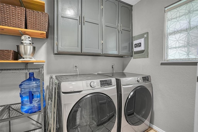 washroom featuring baseboards, a textured wall, cabinet space, and washer and dryer