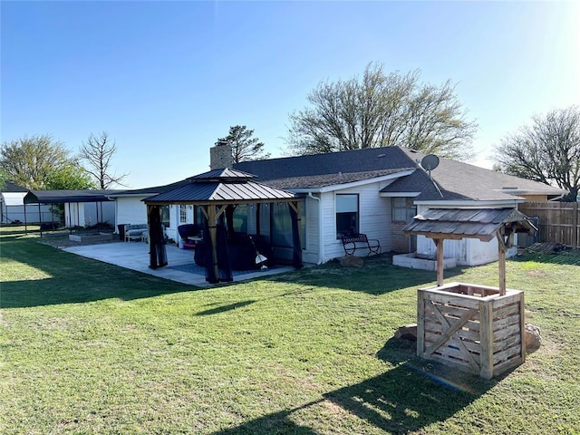 back of property with a chimney, a gazebo, fence, a yard, and a patio