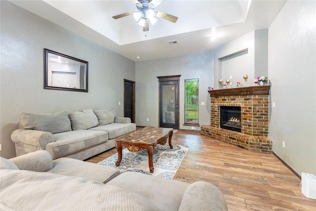 1904 Timber Xing, Yukon, OK 73099 - living area with visible vents, a fireplace, ceiling fan, a raised ceiling, and light wood-style flooring