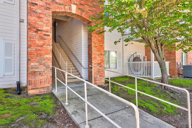 doorway to property featuring brick siding and cooling unit