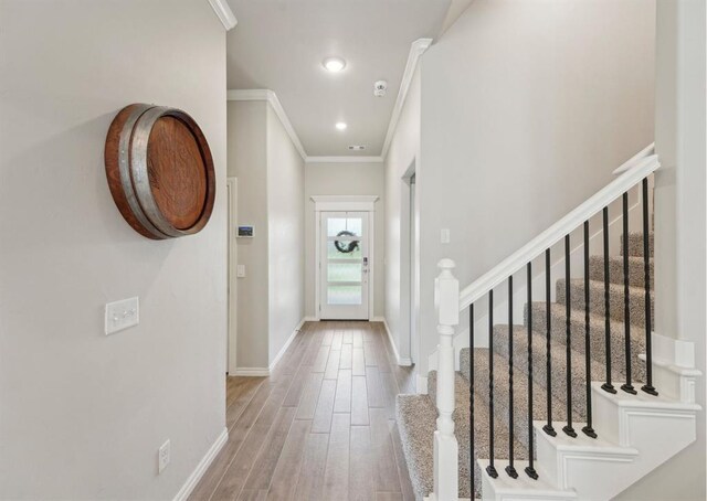 entryway featuring ornamental molding, baseboards, stairway, recessed lighting, and light wood finished floors