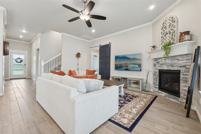 living room with ceiling fan, a fireplace, baseboards, light wood-style floors, and ornamental molding