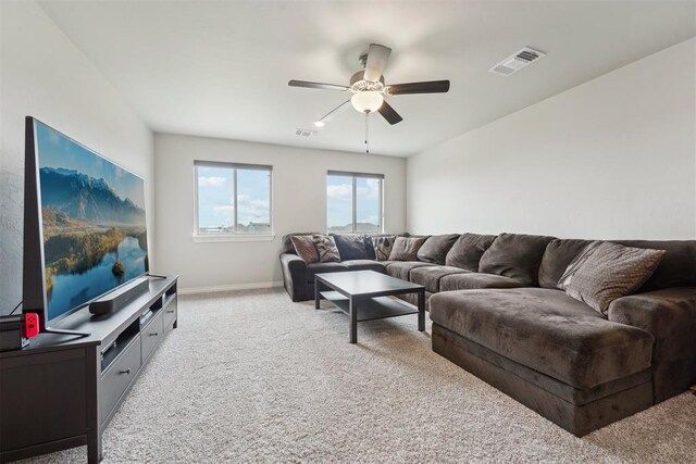 living area with baseboards, ceiling fan, light colored carpet, and visible vents