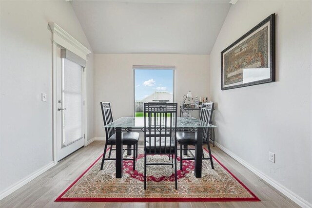 dining room featuring baseboards, vaulted ceiling, and wood finished floors