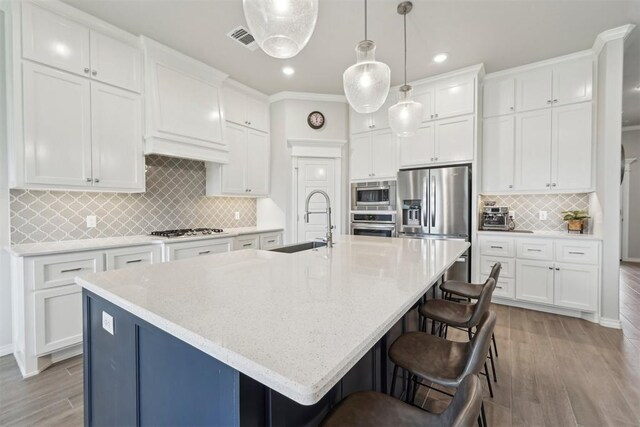 kitchen with visible vents, light wood finished floors, tasteful backsplash, and stainless steel appliances