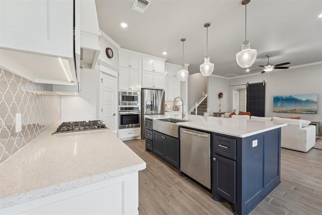 kitchen with appliances with stainless steel finishes, a barn door, a sink, open floor plan, and visible vents
