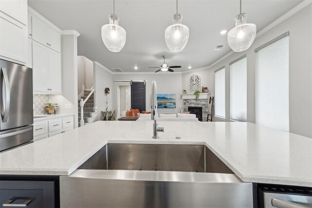 kitchen featuring a sink, crown molding, backsplash, and open floor plan