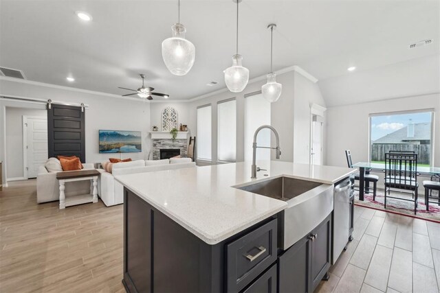 kitchen featuring ceiling fan, visible vents, a barn door, dishwasher, and a sink