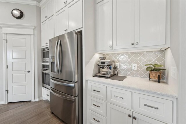 kitchen with white cabinets, appliances with stainless steel finishes, light stone counters, decorative backsplash, and dark wood-type flooring