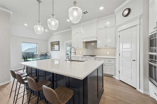 kitchen featuring crown molding, appliances with stainless steel finishes, a sink, backsplash, and visible vents