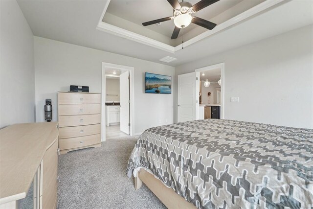 carpeted bedroom with a ceiling fan, connected bathroom, and a tray ceiling