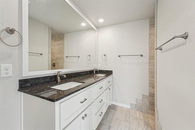 full bath featuring double vanity, a sink, baseboards, and recessed lighting
