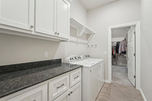 laundry room with cabinet space, separate washer and dryer, baseboards, and light wood finished floors