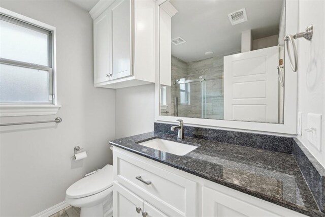 bathroom with vanity, toilet, baseboards, visible vents, and a stall shower