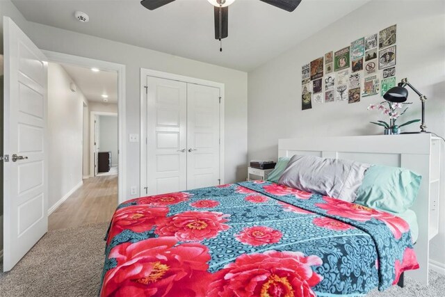 bedroom with ceiling fan, wood finished floors, baseboards, a closet, and carpet