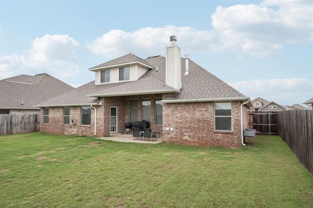 rear view of property featuring brick siding, a patio, a chimney, and a fenced backyard