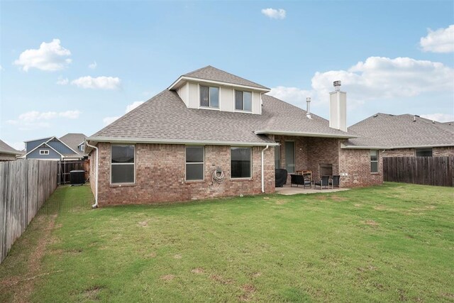 rear view of house featuring roof with shingles, a patio, a yard, and a fenced backyard