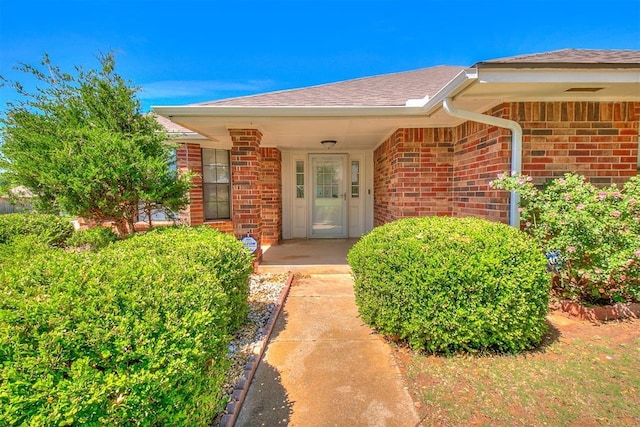10601 Songbird Ln, Oklahoma City, OK 73130 - view of exterior entry with roof with shingles and brick siding