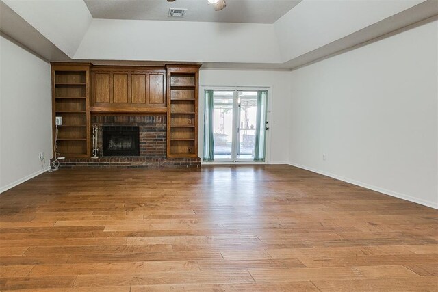 10601 Songbird Ln, Oklahoma City, OK 73130 - unfurnished living room with a brick fireplace, visible vents, light wood-style flooring, and vaulted ceiling