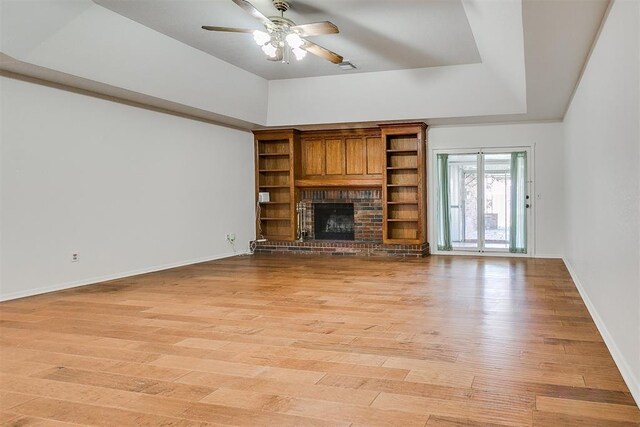 10601 Songbird Ln, Oklahoma City, OK 73130 - unfurnished living room with a ceiling fan, a fireplace, baseboards, a tray ceiling, and light wood-style flooring
