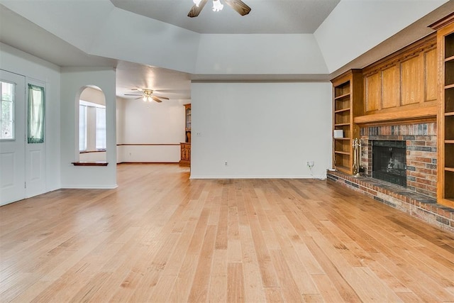 10601 Songbird Ln, Oklahoma City, OK 73130 - unfurnished living room with light wood finished floors, a fireplace, arched walkways, a ceiling fan, and baseboards
