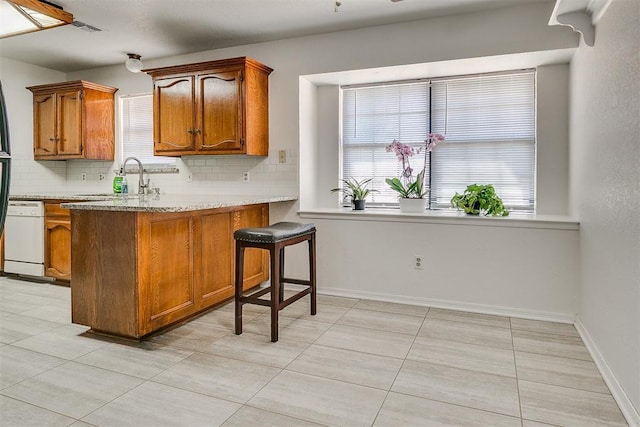 10601 Songbird Ln, Oklahoma City, OK 73130 - kitchen with a sink, tasteful backsplash, brown cabinets, and light tile patterned flooring