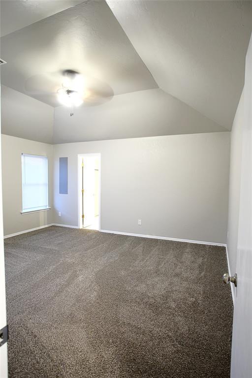 carpeted spare room featuring baseboards, ceiling fan, and vaulted ceiling