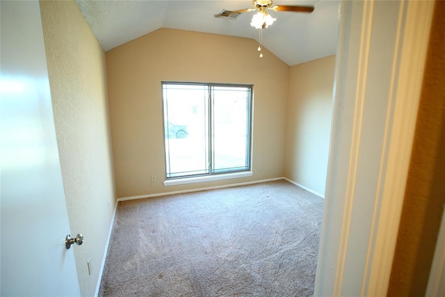 carpeted spare room with ceiling fan, visible vents, baseboards, and vaulted ceiling