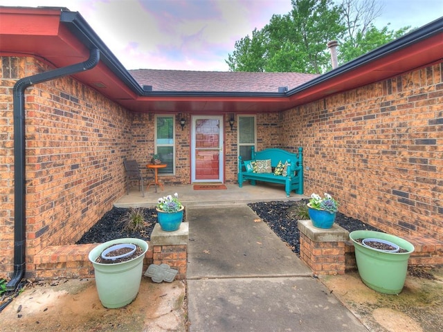 property entrance with brick siding and a shingled roof