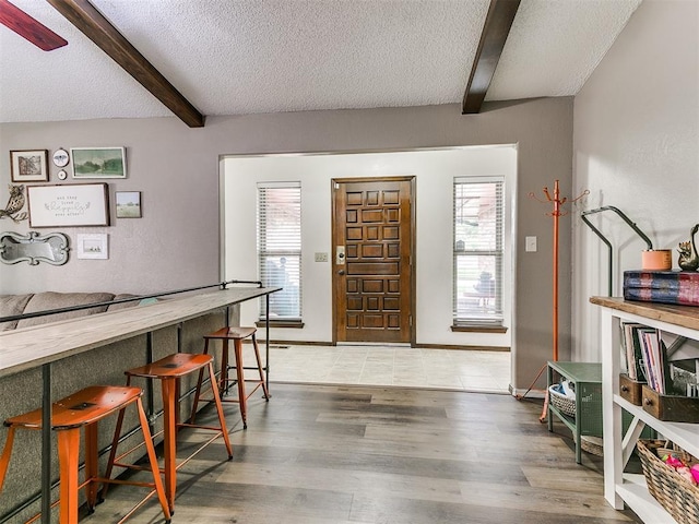 entryway featuring wood finished floors, a textured ceiling, beam ceiling, and a healthy amount of sunlight