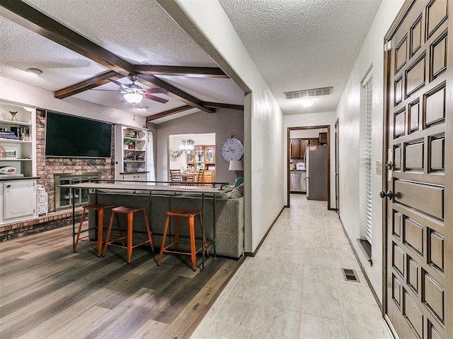 interior space with visible vents, freestanding refrigerator, a textured ceiling, and ceiling fan