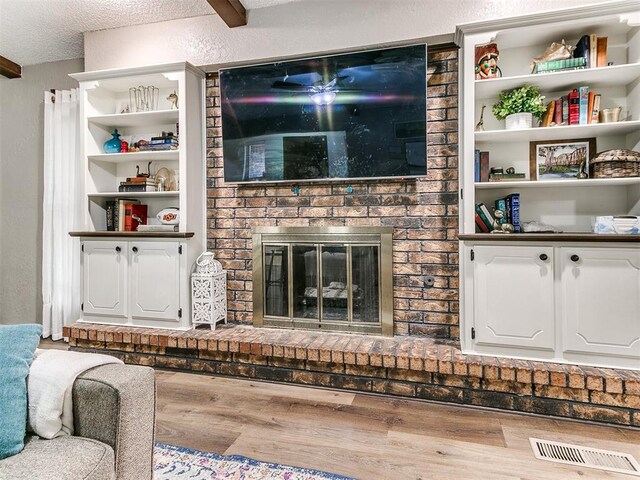 unfurnished living room featuring a textured ceiling, a fireplace, wood finished floors, and visible vents