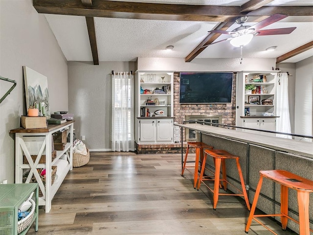kitchen with a textured ceiling, ceiling fan, beam ceiling, and wood finished floors