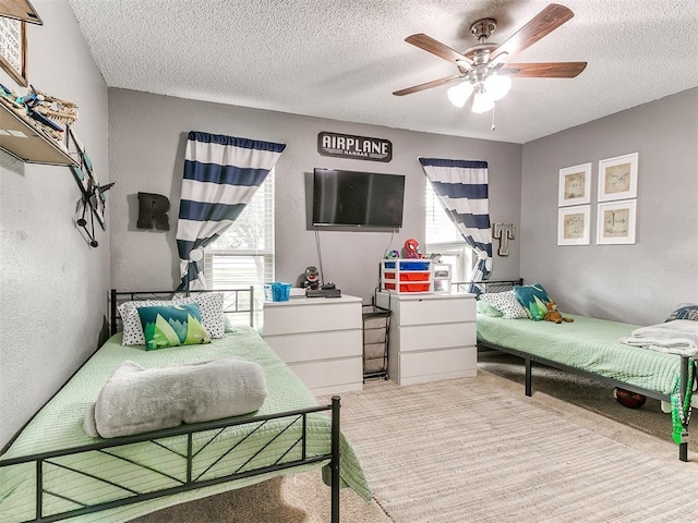 carpeted bedroom featuring a ceiling fan, a textured ceiling, and multiple windows