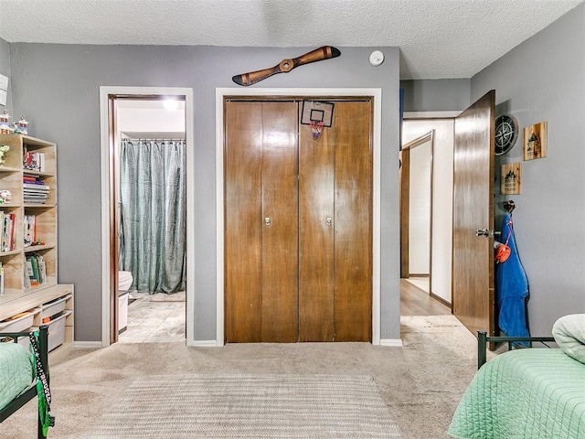 carpeted bedroom with a closet, connected bathroom, and a textured ceiling