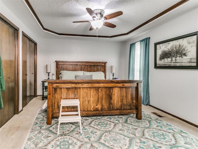 bedroom featuring two closets, a textured ceiling, visible vents, and light carpet