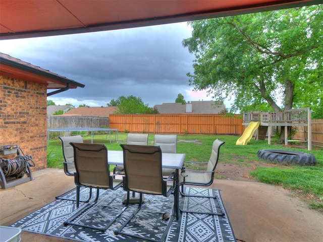 view of patio featuring outdoor dining area, a fenced backyard, a trampoline, and a playground