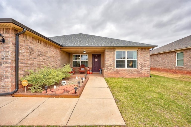 view of front of property featuring brick siding, a shingled roof, and a front yard