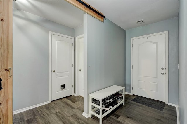 interior space featuring a barn door, baseboards, wood finished floors, and visible vents