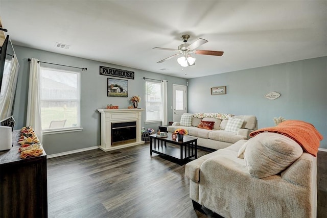 living area with a ceiling fan, visible vents, a fireplace, wood finished floors, and baseboards