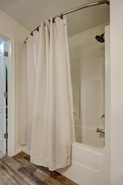 full bath featuring shower / bath combo with shower curtain and wood finished floors