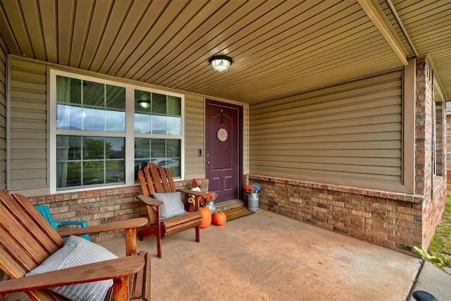 entrance to property with covered porch and brick siding