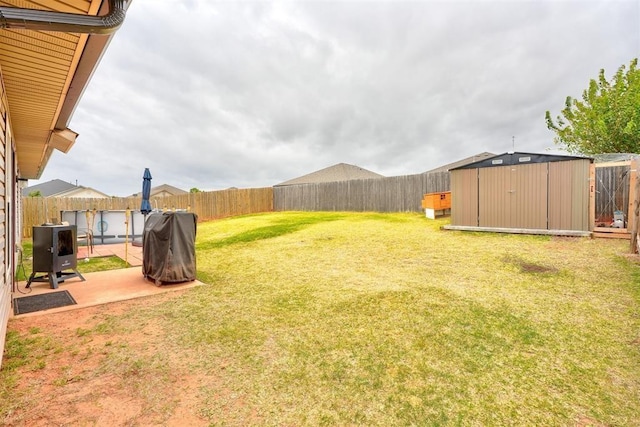view of yard featuring a storage unit, a fenced backyard, a patio area, and an outbuilding