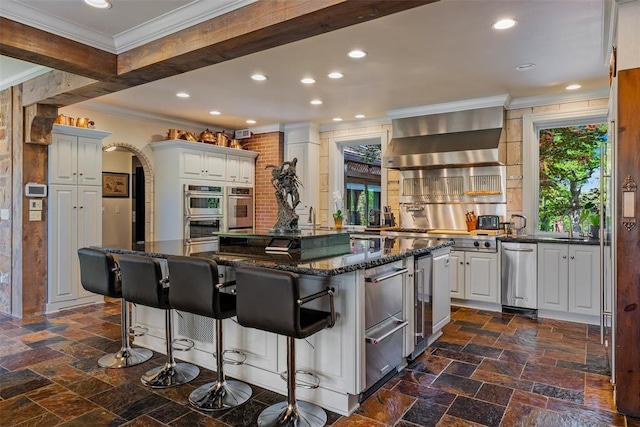 2203 E Wilshire Blvd, Oklahoma City, OK 73111 - kitchen featuring crown molding, wall chimney exhaust hood, a kitchen island, stone tile flooring, and recessed lighting