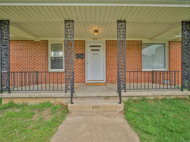 doorway to property featuring brick siding and covered porch