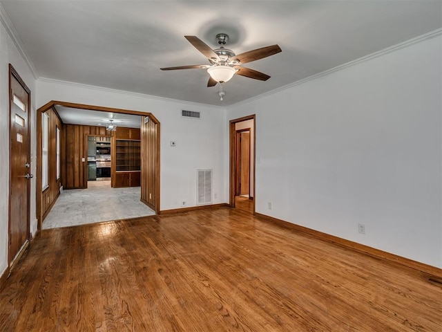 interior space featuring a ceiling fan, visible vents, ornamental molding, and wood finished floors