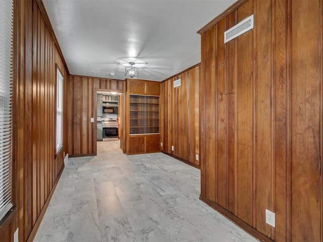 unfurnished living room with visible vents and wood walls