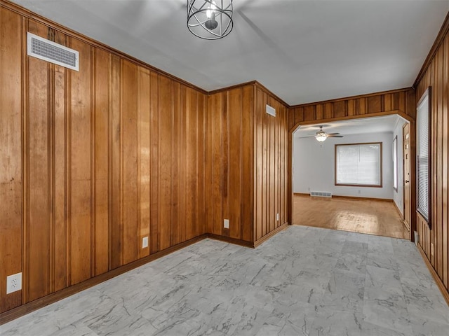 unfurnished room with visible vents, marble finish floor, baseboards, and wooden walls