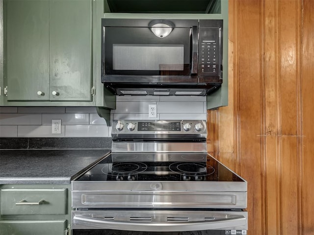 kitchen with stainless steel electric range, black microwave, dark countertops, and green cabinetry