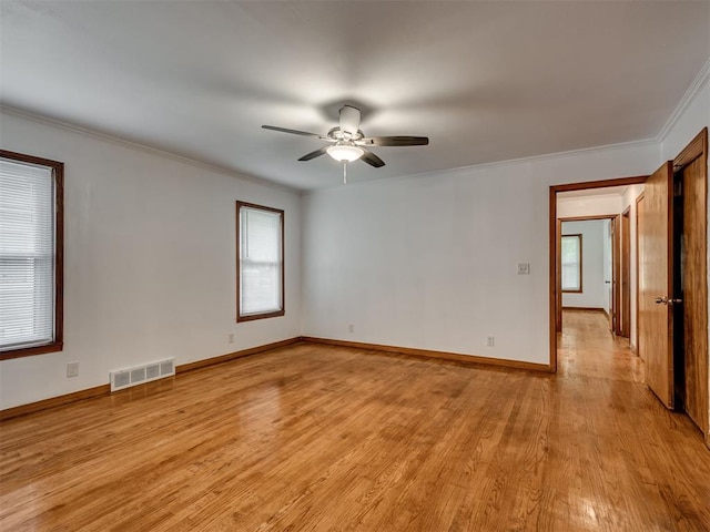 unfurnished room with crown molding, a ceiling fan, light wood-type flooring, and visible vents